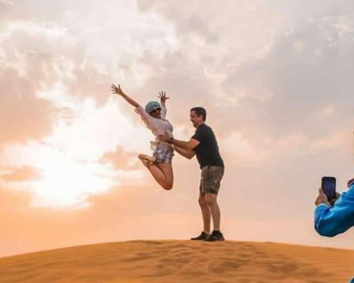 couple jump in Dubai desert dune image